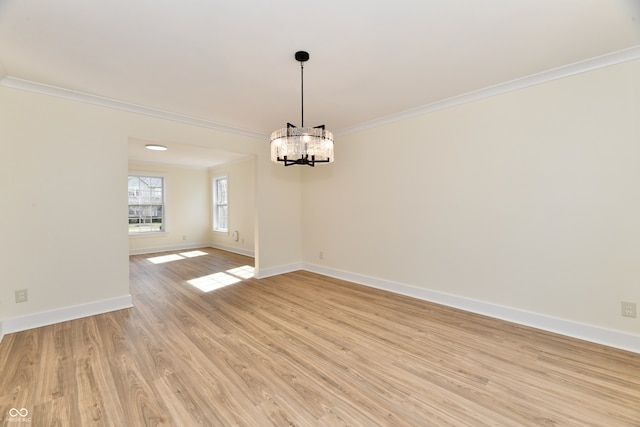 unfurnished room with an inviting chandelier, light wood-style flooring, baseboards, and ornamental molding