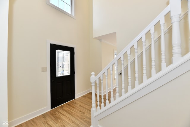 entrance foyer featuring stairs, wood finished floors, baseboards, and a towering ceiling