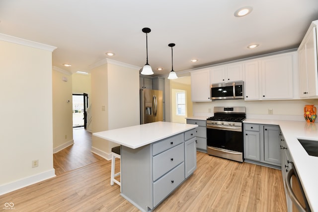 kitchen with a kitchen island, gray cabinets, ornamental molding, appliances with stainless steel finishes, and light wood-type flooring