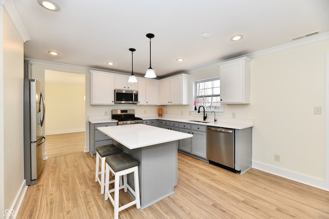 kitchen with visible vents, a center island, ornamental molding, appliances with stainless steel finishes, and a sink