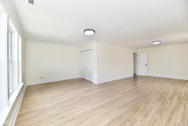 empty room featuring visible vents, baseboards, light wood-style floors, and ornamental molding