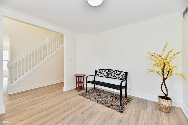 living area featuring wood finished floors, stairs, baseboards, and ornamental molding