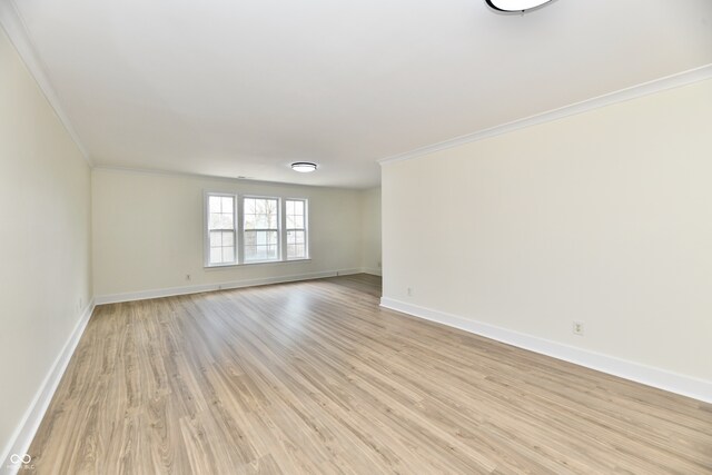 empty room featuring light wood-style flooring, crown molding, and baseboards