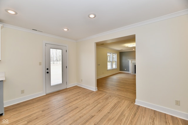 unfurnished room featuring visible vents, crown molding, baseboards, a fireplace with flush hearth, and light wood-style flooring