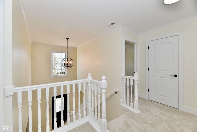 corridor featuring visible vents, an upstairs landing, ornamental molding, carpet, and a chandelier