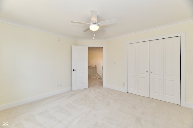 unfurnished bedroom with crown molding, baseboards, carpet flooring, a closet, and a ceiling fan