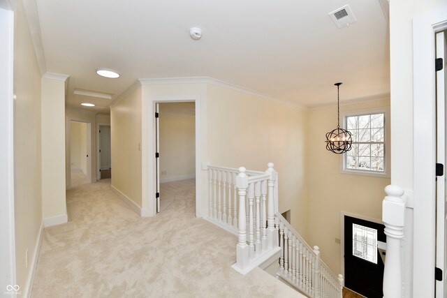 corridor with visible vents, baseboards, crown molding, carpet flooring, and an upstairs landing