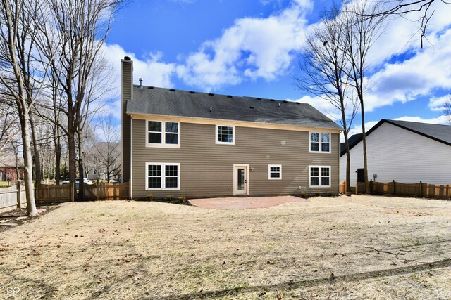 rear view of property featuring a patio, a chimney, and fence