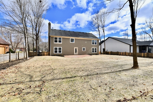 rear view of house featuring a patio, a chimney, and a fenced backyard