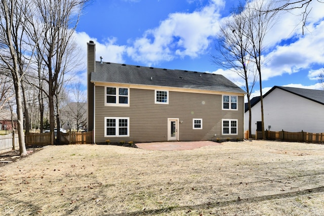 rear view of property with a patio, a chimney, and fence