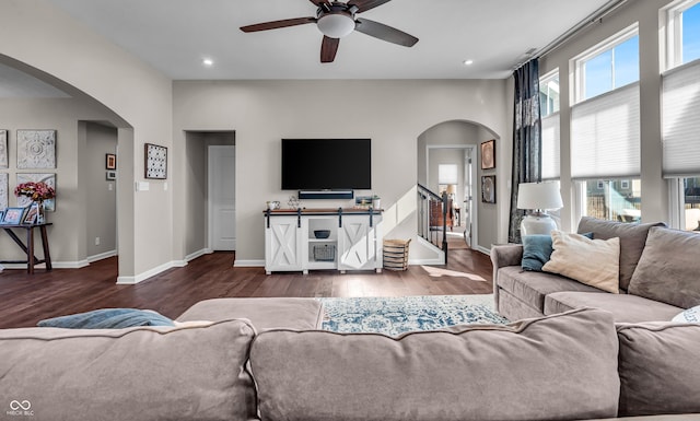 living room featuring arched walkways, wood finished floors, and baseboards