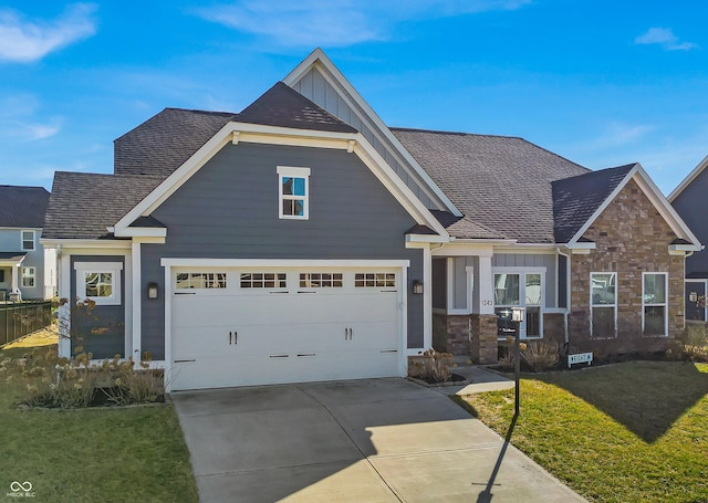 craftsman house featuring driveway, stone siding, board and batten siding, and a front yard