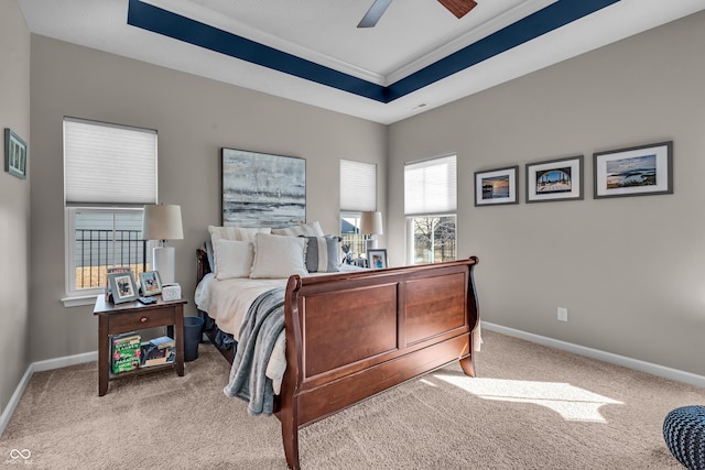 bedroom featuring light carpet, visible vents, baseboards, a raised ceiling, and ceiling fan