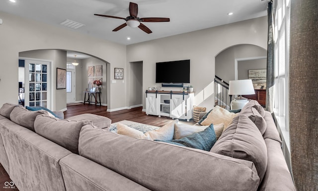 living room featuring visible vents, arched walkways, baseboards, dark wood-style floors, and stairs