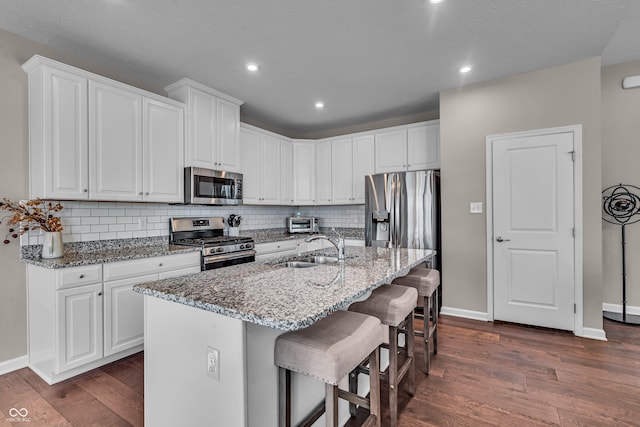 kitchen featuring appliances with stainless steel finishes, dark wood-style flooring, a sink, and backsplash