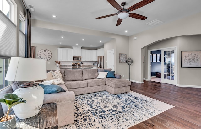 living room featuring arched walkways, dark wood finished floors, recessed lighting, visible vents, and baseboards