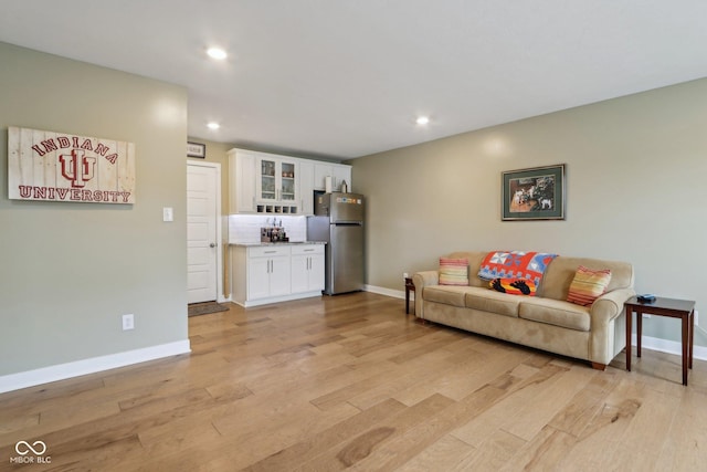 living room with recessed lighting, baseboards, and light wood-type flooring