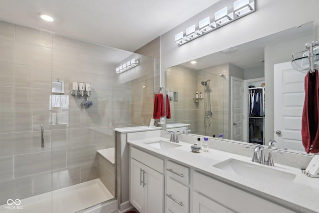 full bath featuring a sink, a spacious closet, double vanity, and a shower stall