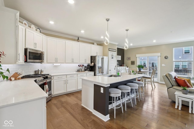 kitchen with light wood-style floors, backsplash, appliances with stainless steel finishes, and a breakfast bar