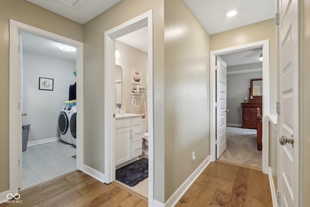 hall featuring baseboards, light wood-style flooring, and washer and clothes dryer