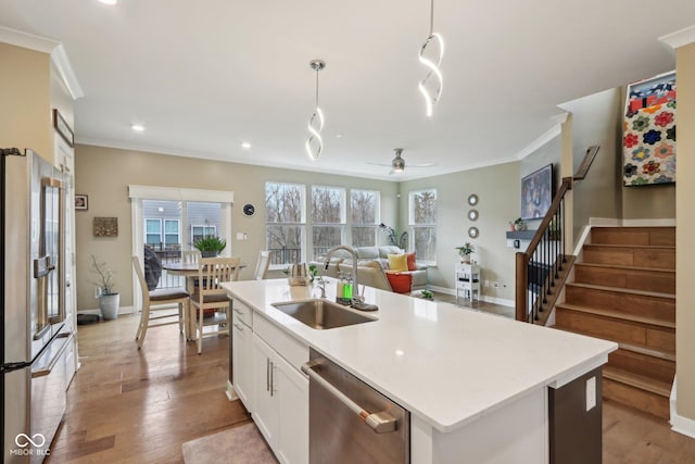 kitchen with a sink, stainless steel appliances, light wood-style flooring, and crown molding