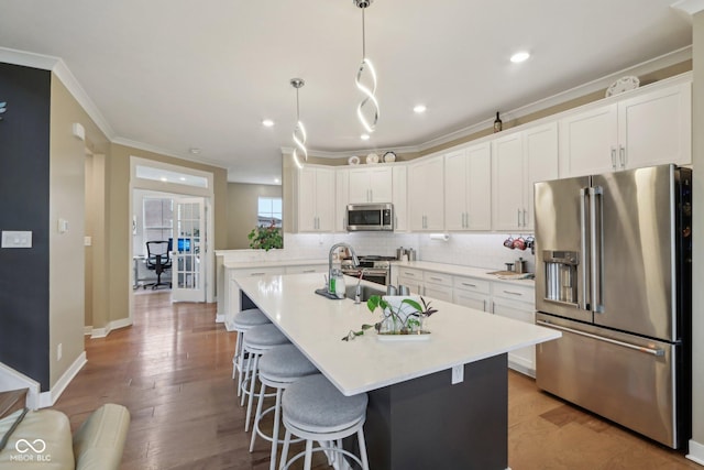 kitchen with a center island with sink, tasteful backsplash, white cabinetry, crown molding, and high end appliances