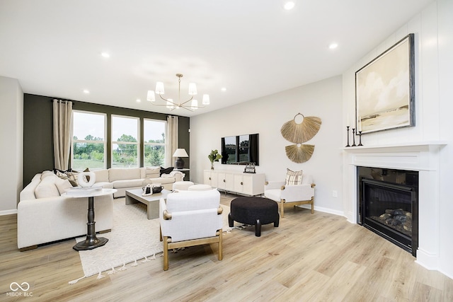 living room with recessed lighting, a glass covered fireplace, light wood-style flooring, and an inviting chandelier