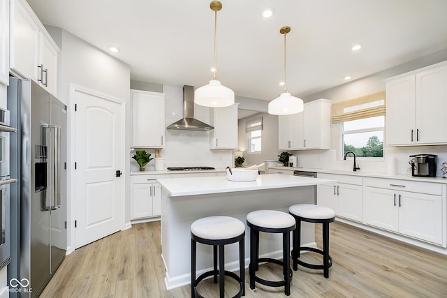 kitchen with white cabinetry, high end refrigerator, and wall chimney exhaust hood