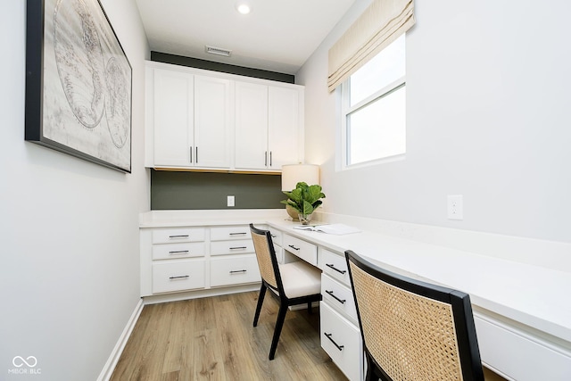 office featuring visible vents, built in study area, light wood-style flooring, and baseboards