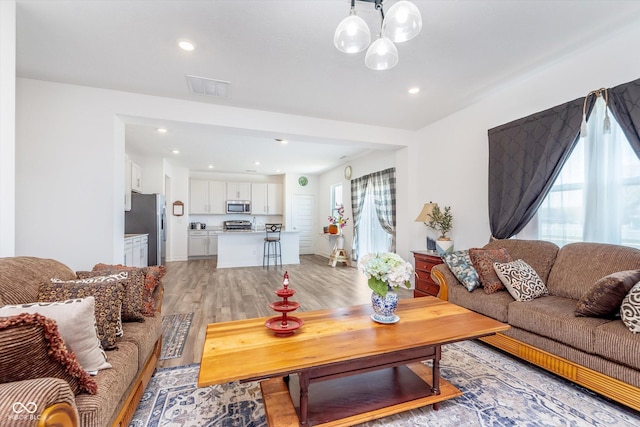 living area with a chandelier, light wood-style floors, visible vents, and recessed lighting