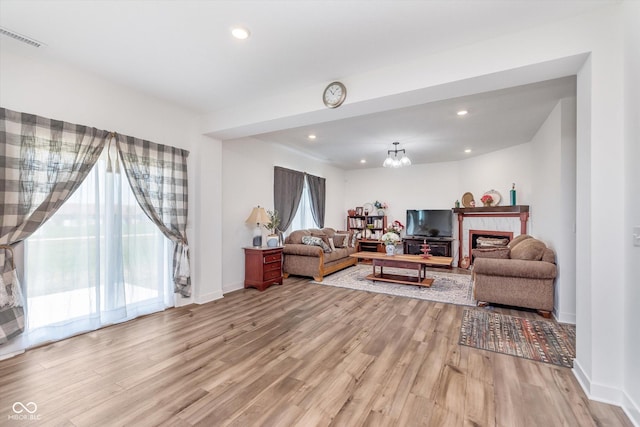 living area featuring light wood-style flooring, visible vents, recessed lighting, and a fireplace