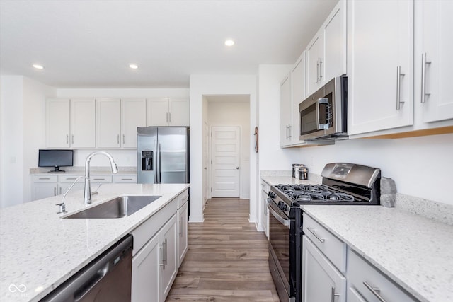 kitchen with light wood-type flooring, light stone countertops, a sink, and appliances with stainless steel finishes