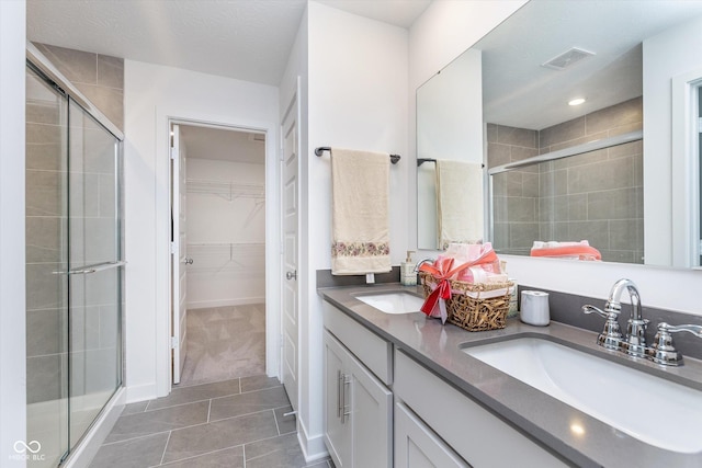 bathroom featuring visible vents, a stall shower, and a sink