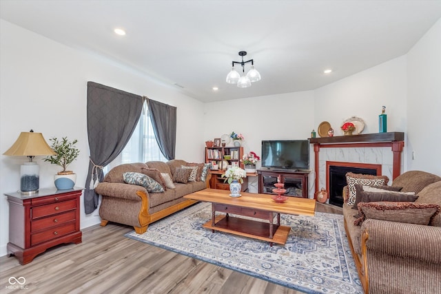 living room featuring a tiled fireplace, wood finished floors, an inviting chandelier, and recessed lighting