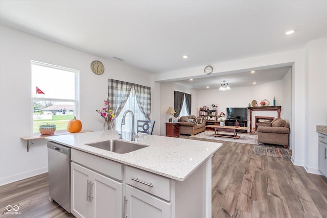 kitchen with dishwasher, an island with sink, a sink, and light wood-style flooring