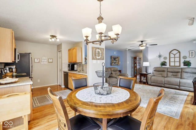 dining area featuring light wood-type flooring, baseboards, and ceiling fan with notable chandelier