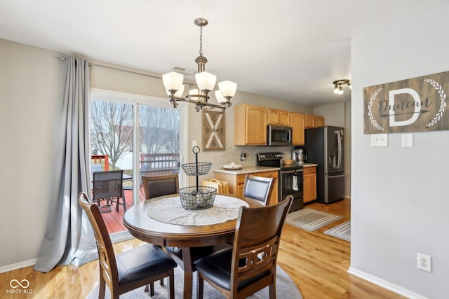 dining room featuring an inviting chandelier, light wood-style flooring, and baseboards