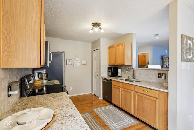 kitchen with light wood finished floors, backsplash, appliances with stainless steel finishes, a sink, and baseboards