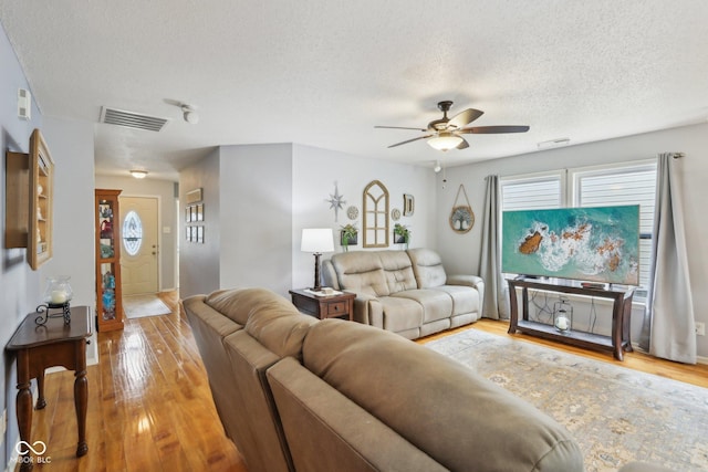 living area with a textured ceiling, visible vents, and hardwood / wood-style floors