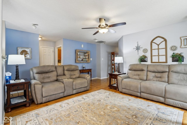 living room featuring a ceiling fan, visible vents, baseboards, and wood finished floors