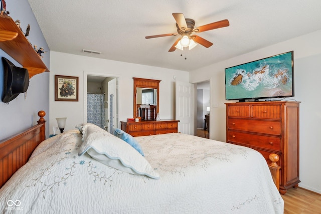 bedroom featuring a ceiling fan, light wood-type flooring, visible vents, and connected bathroom