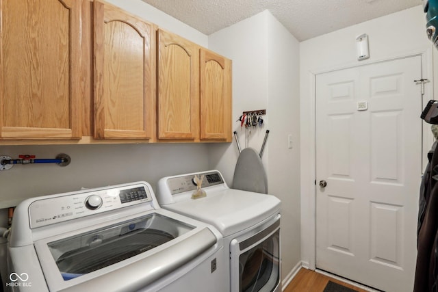 clothes washing area with cabinet space, a textured ceiling, and separate washer and dryer