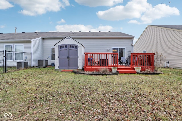 rear view of property with a lawn, fence, a storage unit, a wooden deck, and an outdoor structure