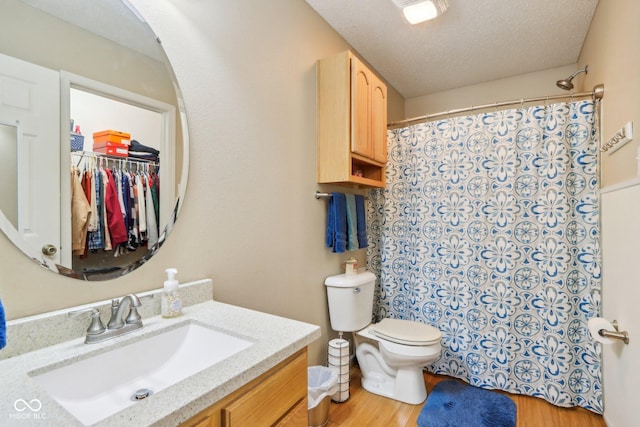 full bath featuring a shower with shower curtain, toilet, a textured ceiling, vanity, and wood finished floors