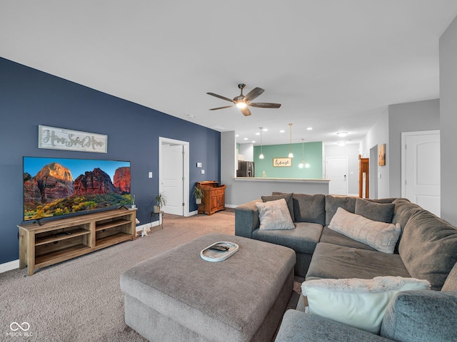 living area featuring baseboards, a ceiling fan, and light colored carpet