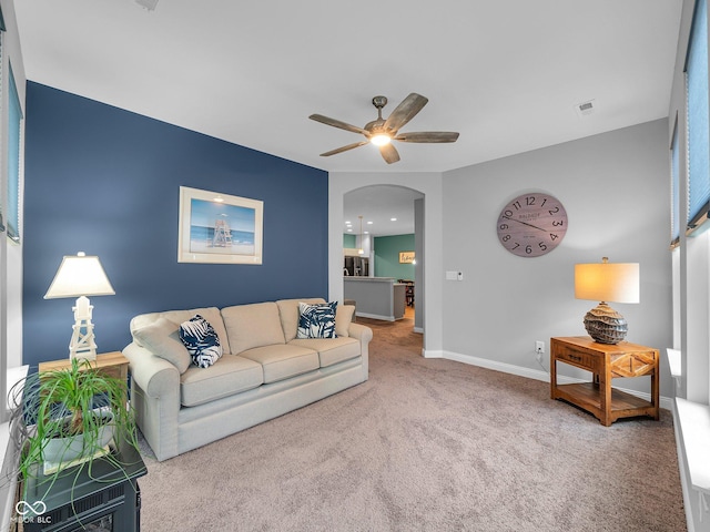 living room with visible vents, arched walkways, a ceiling fan, baseboards, and carpet flooring