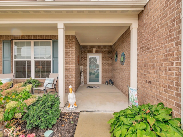 doorway to property with covered porch and brick siding