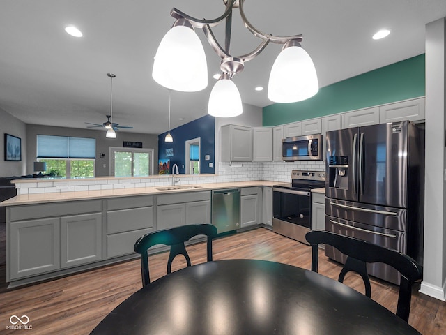 kitchen with light countertops, decorative backsplash, appliances with stainless steel finishes, a sink, and wood finished floors