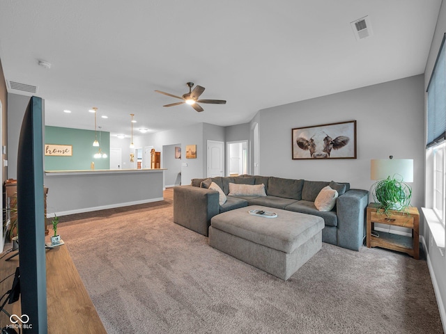 living area featuring baseboards, visible vents, ceiling fan, and wood finished floors