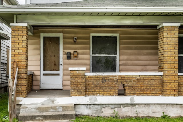 property entrance featuring brick siding and roof with shingles